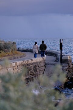 Couple walking together on a stone seaside pathway