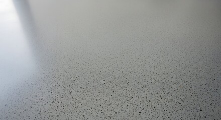 A close up view of a speckled light gray surface with a blurred light source in the upper left
