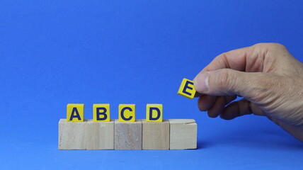 Due file di cubi di legno con le lettere A, B, C, D ed E, tenuti da una mano umana. Concetto di gestione e definizione delle priorit&agrave; delle attivit&agrave;. Definizione delle priorit&agrave; di qualsiasi attivit&agrave;.