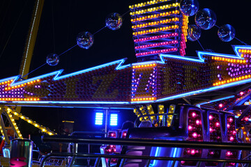 Vibrant fairground ride with glowing neon lights and sparkling disco balls illuminating the night sky at Goose Fair, Nottingham, England.