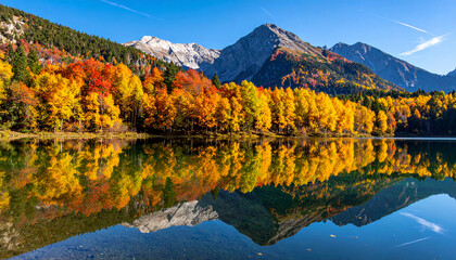Naklejka premium Reflection of vibrant autumn trees in crystal-clear mountain lake with colorful foliage and clear blue sky
