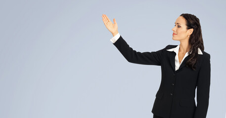 Profile portrait of smile cute businesswoman woman wear black corporate suit, pointing showing upward and looking same direction. Business concept. Isolated gray grey background with free text space