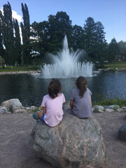 Children Sitting Together by Park Fountain