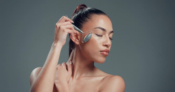 Woman, jade roller and skincare in studio for beauty, mock up space or circulation on background. Person, model and tools with routine for self care, dermatology and massage for lymphatic drainage