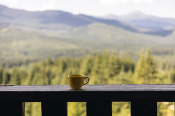Yellow cup on balcony with mountain view and space for text or quote.