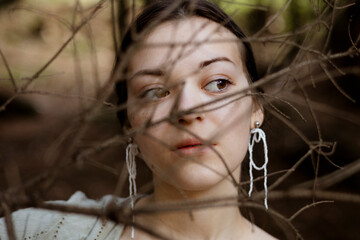 Thoughtful young woman face closeup in forest background.