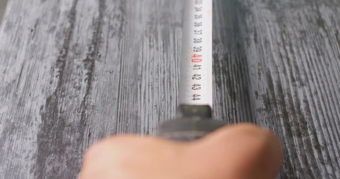 First person view measuring a wooden surface with a tape measure