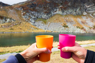 Tea in the mountains. Two bright cups of tea in the background a mountain's lake, which is located at the bottom of the mountain.