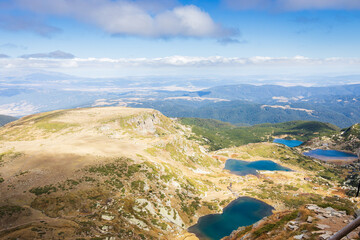 A scenic view of the mountains' lakes and the mountains on a sunny day. Picturesque blue sky with...