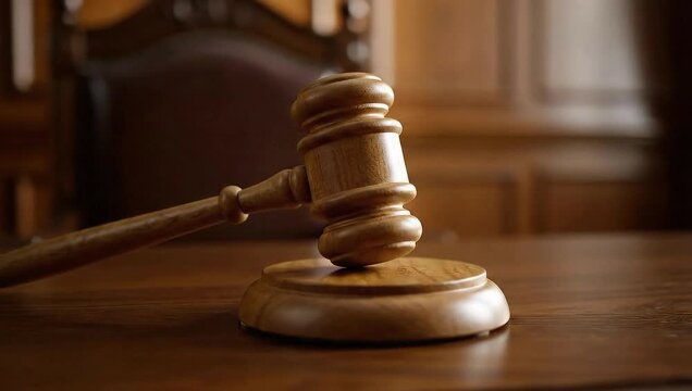 Wooden gavel resting on desk in law courtroom background  