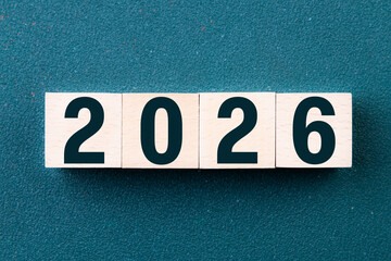 2026 Happy New Year. Wooden cube block 2026 greeting card on green. Concept 2026 New Year background. Business, resolutions, goals, inspiration, success, ideas
