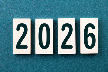 2026 Happy New Year. Wooden cube block 2026 greeting card on green. Concept 2026 New Year background. Business, resolutions, goals, inspiration, success, ideas