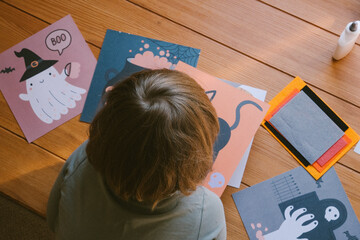 The child is making Halloween crafts. Preparing for Halloween. 