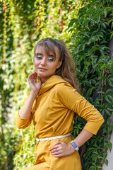 Fototapeta premium Portrait of a blonde woman in a yellow dress on the city streets. Autumn