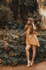 Naklejka premium Portrait of a blonde woman in a yellow dress on the city streets. Autumn