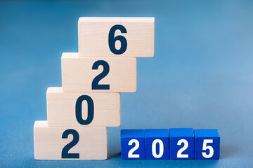 2026 Happy New Year. Wooden cube block change from 2025 to 2026 on blue. Concept 2026 New Year background. Business, resolutions, goals, inspiration, success, ideas
