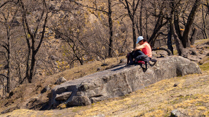 young woman resting on a large rock after a hiking long day in Tafi del Valle, Tucuman