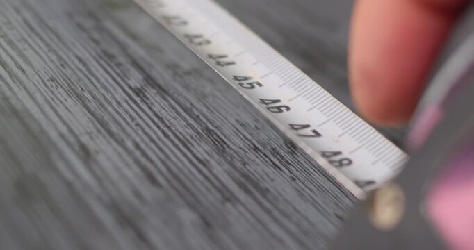 Worker using measuring tape on wooden surface
