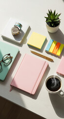 Overhead shot of a workspace with a pink notebook, coffee, succulent, and stationery on a white table, creating a bright and organized aesthetic, perfect for planning and creative projects