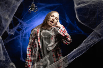 Creepy scary zombie man with ugly makeup pointing phone gesture say call me standing on spooky...