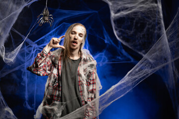 Creepy scary zombie man with ugly makeup showing small size gesture in measure product standing on...