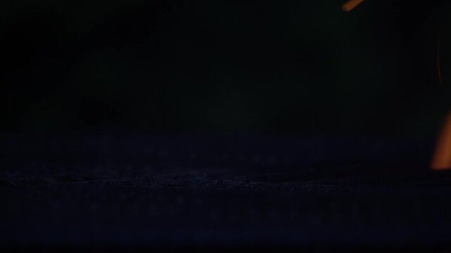 Flames rising through metal grill grates in a dark scene, capturing intense heat, fire motion, and dramatic barbecue atmosphere with strong contrast and texture.