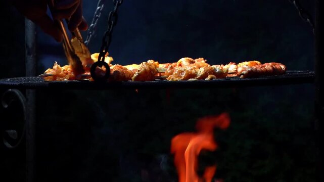 Outdoor grilling scene with meat cooking over open flame, capturing heat, smoke, and rustic barbecue atmosphere with dramatic firelight and authentic cooking action.