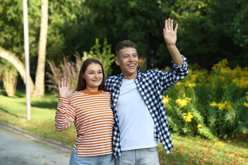 Couple waving goodbye in park on sunny day