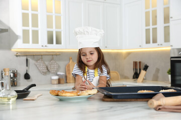 Choice of profession. Little girl with pastries pretending to be chef in kitchen