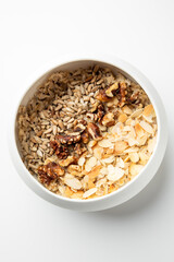 Healthy breakfast bowl with plain oatmeal topped with sunflower seeds, walnuts, and sliced almonds. Minimalist composition, top view, natural light, clean eating concept.