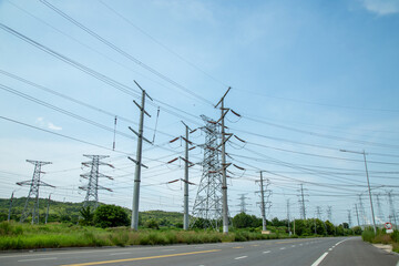 High-voltage transmission towers along a rural road under blue sky