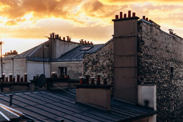 Classic Paris rooftops with chimneys and mansard windows at sunset.