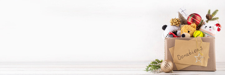 Donating gifts and toys to charity for Christmas holiday concept. Tradition holiday toys drive, cardboard box full with with kids toys, gifts, Christmas decorations, baubles and sweets, copy space