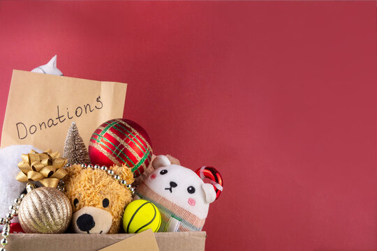Donating gifts and toys to charity for Christmas holiday concept. Tradition holiday toys drive, cardboard box full with with kids toys, gifts, Christmas decorations, baubles and sweets, copy space