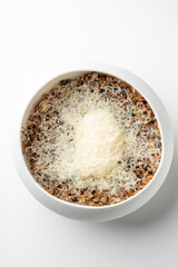 White bowl with cooked minced food topped with finely grated cheese, isolated on white background. Simple rustic presentation ideal for culinary, recipe, or food styling themes