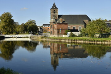 Fototapeta premium L'église Saint-Jean Baptiste de Houdeng-Aimeries se reflétant dans les eaux de l'ancien canal du Centre (La Louvière)