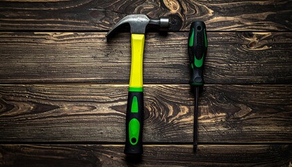 A hammer and screwdriver rest side-by-side on a dark wooden surface with a natural grain pattern