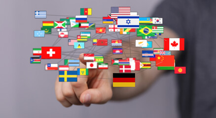 A hand touches connected flags representing different nations and countries, symbolizing global connection, international relations, and unity.