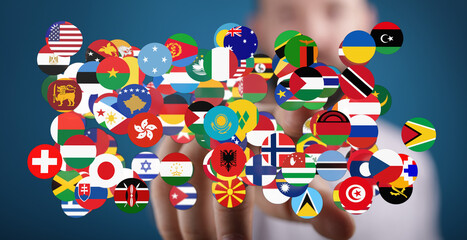 Obraz premium Diverse flags representing countries around the world floating near a person's hand, symbolizing globalism and interconnectedness. Ideal for int