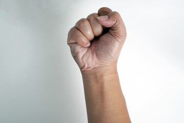 A person's hand is raised in a tight fist against a white background. This powerful image is ideal for concepts of strength, determination, protest, or success.

