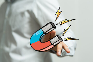 Hand holding a powerful magnet, symbolizing customer attraction and strong marketing.