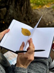 woman writes on a notebook in an autumn park