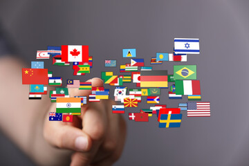 Hand pointing at a diverse collection of national flags, representing global unity and...