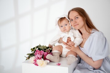 mom with a baby little daughter with peony flowers on a white isolated background, space and room for text