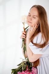a young beautiful girl with peony flowers on a white isolated background, space and room for text