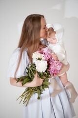 mom with a baby little daughter with peony flowers on a white isolated background, space and room for text
