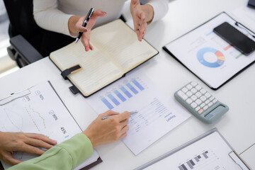 Business professionals analyzing financial reports collaborating planning strategy office meeting table data charts documents pens hands calculator smartphone