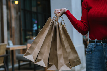 A person holding multiple brown paper shopping bags, representing retail, eco-friendly packaging, shopping lifestyle, and consumerism.