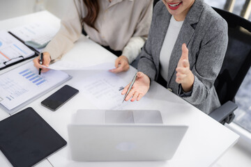 Asian businesswomen discussing data analysis project strategy reviewing documents collaborating modern office workspace