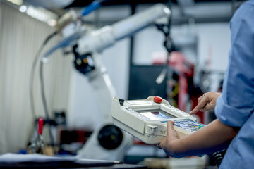 Robot Control Panel: Hand Operation of Industrial Automation Equipment Automation Interface: Engineer Using Handheld Controller for Robot Programming Close Up of Hand Operating Control Panel.